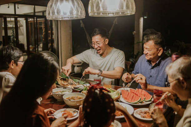 Local Thai-Chinese family having party dinner-stock photo kindness, Great son and great moment! Large modern Thai-Chinese family sharing healthy food together while staying at home for birthday at local home town, Chinese New Year party dinner at home family reunion stock pictures, royalty-free photos & images
