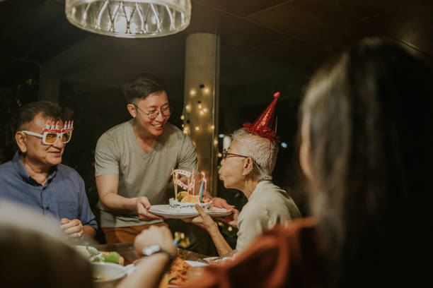 deseándole suerte, hijo le da pastel de cumpleaños a su madre -foto de archivo - birthday party adult women fotografías e imágenes de stock