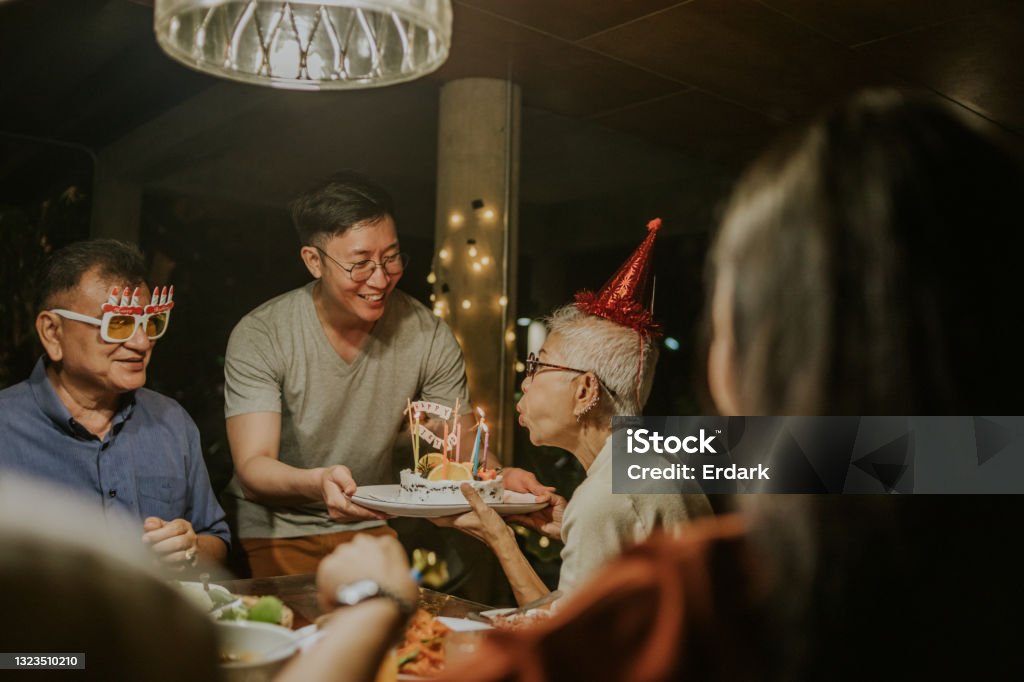 Wishing you luck, Son gives birthday cake to his mother -Stock photo 64 years old for hipster mother, All members of Thai family come to see each other for grandmother birthday party Birthday Stock Photo