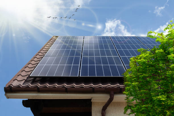 Solar photovoltaic panels on a house roof. ECO CONCEPTUAL Concept clean power energy - solar panel on the roof. Green tree rooftop solar stock pictures, royalty-free photos & images