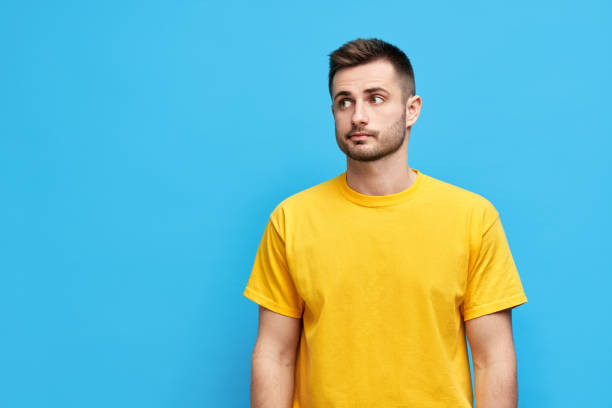 istock Doubtful thoughtful man looking aside to copy space over blue background 1323511561