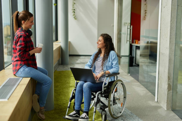 istock Disabled computer programmer discussing with female coworker in office hallway 1323511974