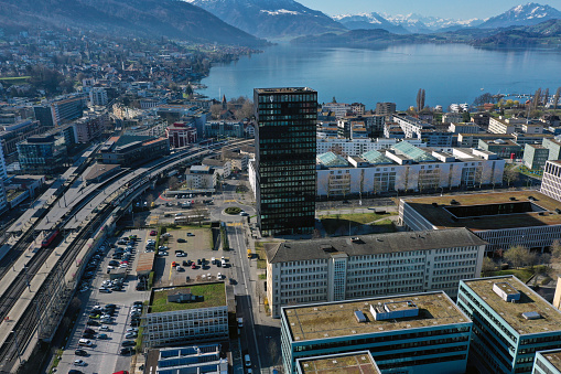 Zug the small town in central switzerland with arround 30'000 residents captured during a beautiful day in springtime. The image shows the modern part of the city with several office buildings. In the background to see the lake of zug and some snow covered mountains.