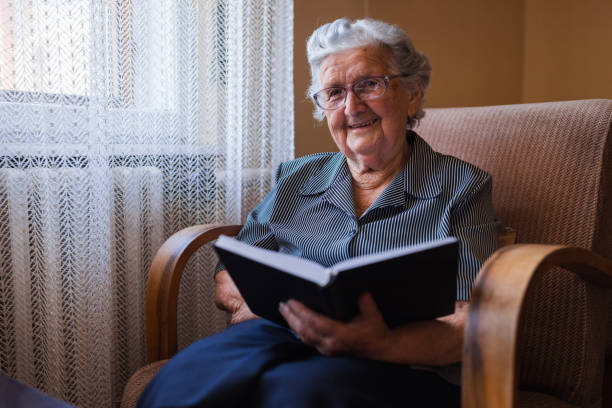 istock Joly old woman reading a book at home 1323518915