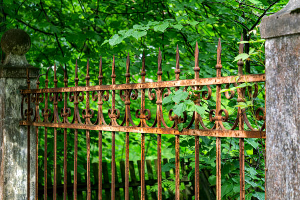 istock There is an old forged, rusty fence between the concrete pillars. 1323519420