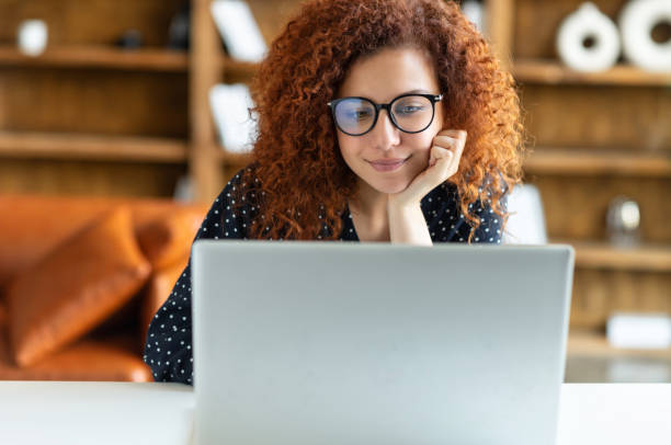 istock Red-haired curly pretty female freelancer using laptop 1323521187