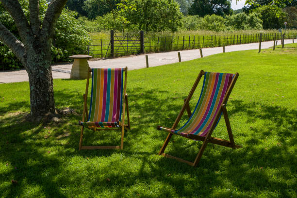 istock Two colourful deck chairs on a shady spot by a tree in an English meadow 1323523492