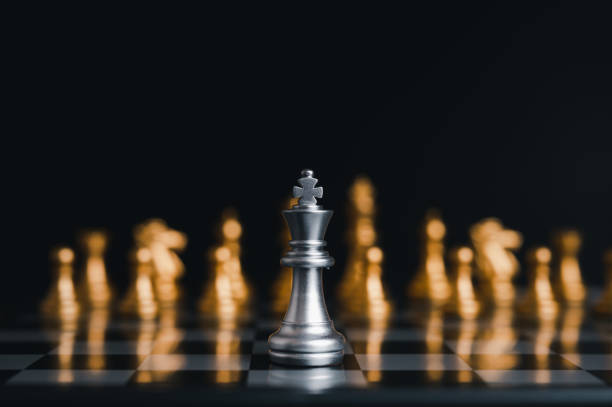 istock Silver king winner surrounded with silver chess pieces on chess board game competition.concept strategy, leadership and success business. 1323526392