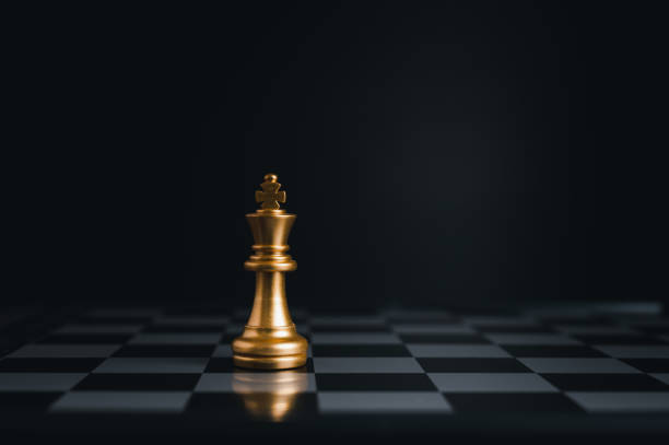 istock Gold king winner surrounded with silver chess pieces on chess board game competition.concept strategy, leadership and success business. 1323526435