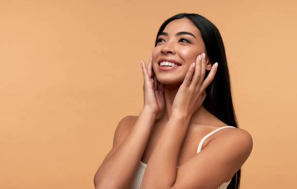 Beauty woman on background Young Asian woman with clean healthy glowing skin in white top isolated on beige background. Facial skin care concept, spa, cosmetology, plastic surgery. asian american model stock pictures, royalty-free photos & images