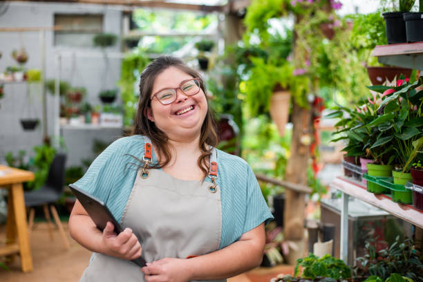 Social inclusion - woman with down syndrome working in small business using digital tablet Social inclusion - woman with down syndrome working in small business social inclusion photos stock pictures, royalty-free photos & images