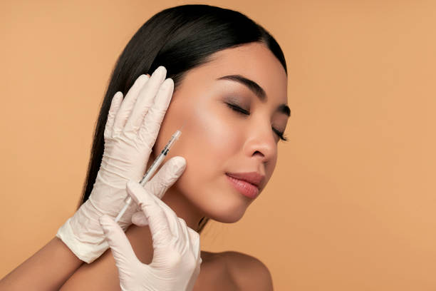 Beauty woman on background Young Asian woman with clean radiant skin gets botox injections for contour tightening, lip augmentation on a beige background. Spa care, facial skin care, beauty cosmetology. botulinum toxin injection stock pictures, royalty-free photos & images