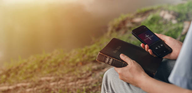 mujer buscando libro de la biblia en el teléfono inteligente para estudiar las enseñanzas de dios - teachings fotografías e imágenes de stock