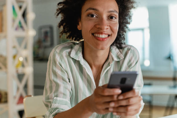 istock Beautiful woman is using mobile phone at home 1323533334
