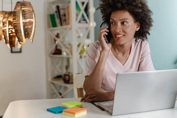 istock Woman is using laptop and talking on the phone 1323534242