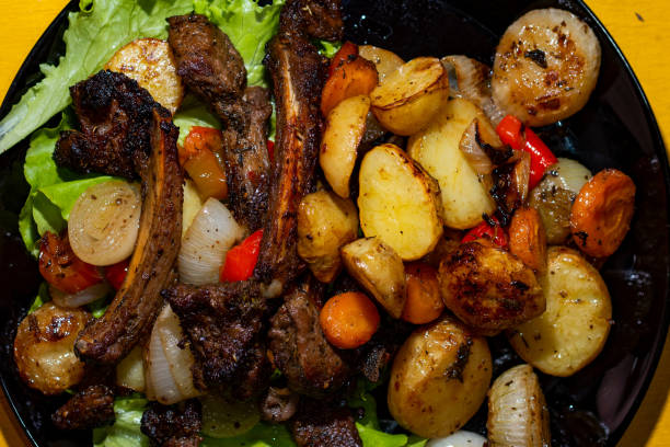 istock Grilled lamb ribs and baked vegetables on black plate over . Top view, flat lay 1323534518