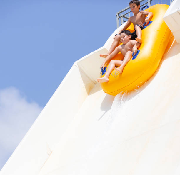 istock kids having fun sliding in water park 1323537863