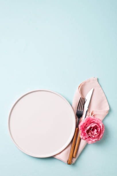 istock Tableware setting with fork, knife, napkin and flower on blue background, 1323541907