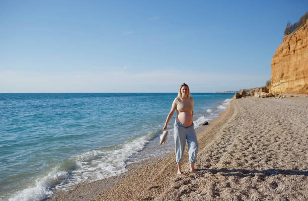 istock a pregnant woman standing on the seashore 1323543020