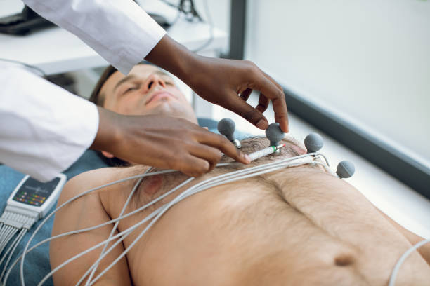 imagen recortada de una mujer afroamericana doctora o enfermera pegando electrodos holter y vacío en el pecho del paciente masculino joven en el hospital. ecg y concepto de salud cardíaca. chequeo anual. - pulse trace electrode human heart holter fotografías e imágenes de stock