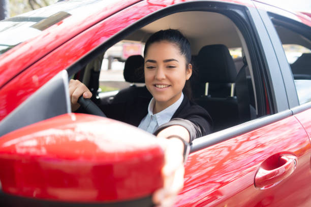 istock Woman moving rear view wing mirror in car. 1323543723