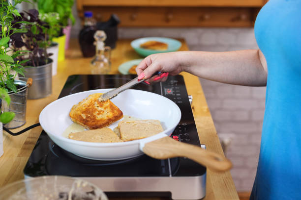 Woman preparing french toast flavored with fresh berry fruits and drizzled with maple syrup