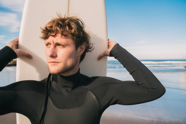 istock Surfer standing at the beach with surfboard. 1323545279