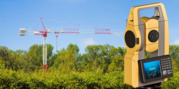istock Red and white tower crane surrounded by nature and 3D rendering of a geodesic device, called Total Station, used for the survey of topographic maps and topographical survey - concept image with a cadastral map on foreground 1323548949
