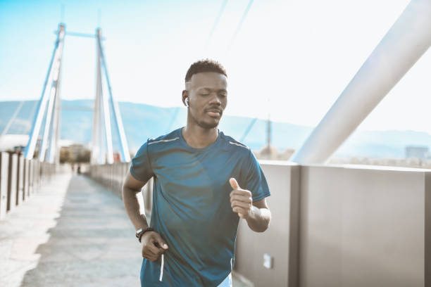 istock Smiling African Male Enjoying Music While Jogging On Bridge Outside 1323549147
