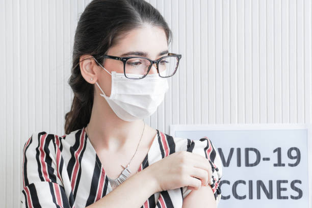 nahaufnahme gesicht der frau vorbereitung ihre schulter an, während immer covid-impfstoff in klinik oder krankenhaus, frau trägt schutzmaske gegen covid-19. - isolated cold virus head and shoulders cold and flu stock-fotos und bilder