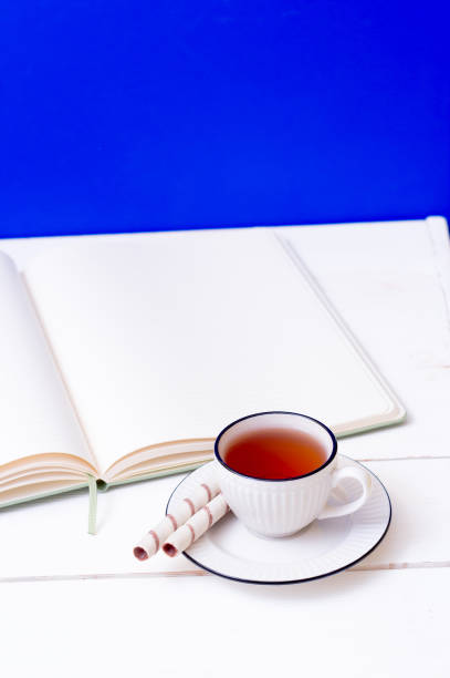 istock A cup of tea, a notebook and sweet wafer rolls. Snack while studying. Education. Homework at school and university. Blue background 1323551723