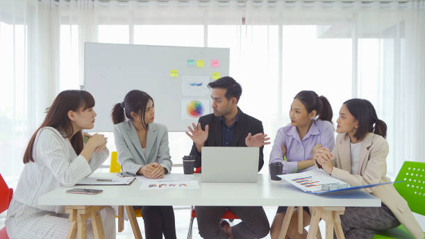 istock Group of Asian business people meeting with board, communicate, discuss documents, and working in a meeting room in office seminar, present ideas with colleagues. People lifestyle. Corporate teamwork 1323552370