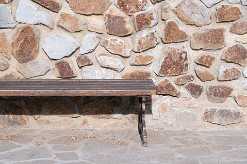 a vacant bench by the stone wall. High quality photo