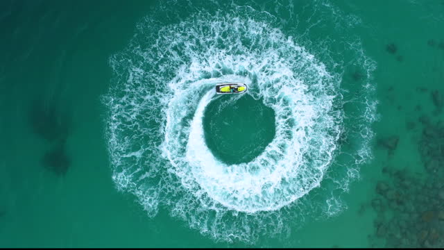 People are playing a jet ski in the sea. Aerial view and top view.