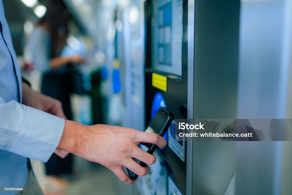 Close up of a young Asian man using contactless payment via smartphone to pay for her shopping at self-checkout kiosk in airport Kiosk Stock Photo