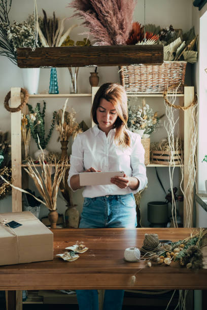 istock Beautiful Female Online Store Owner Checking New Orders on Digital Tablet 1323555670