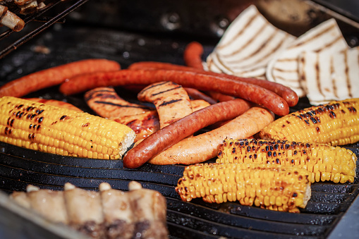 Process of preparing sausages and corn on Outdoor Grill , selective focus. Summer picnic concept