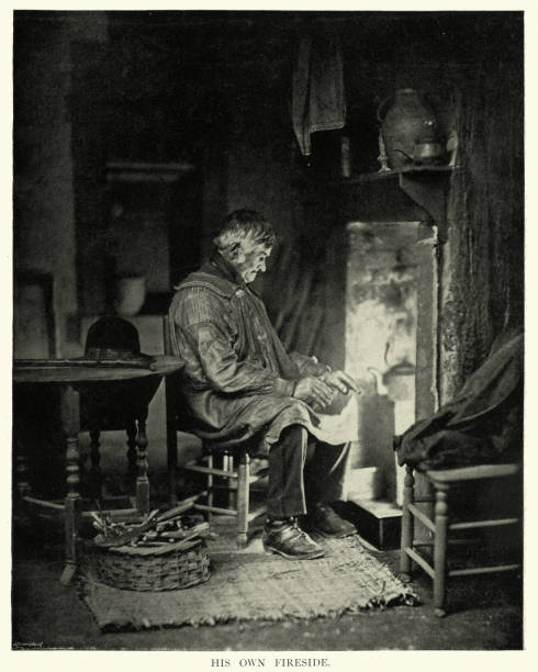 istock Old man warming himself before open fire, kettle boiling, Victorian vintage photograph 1323564630