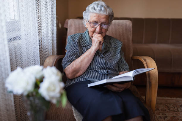 istock Concentration old woman reading a book at home 1323566047