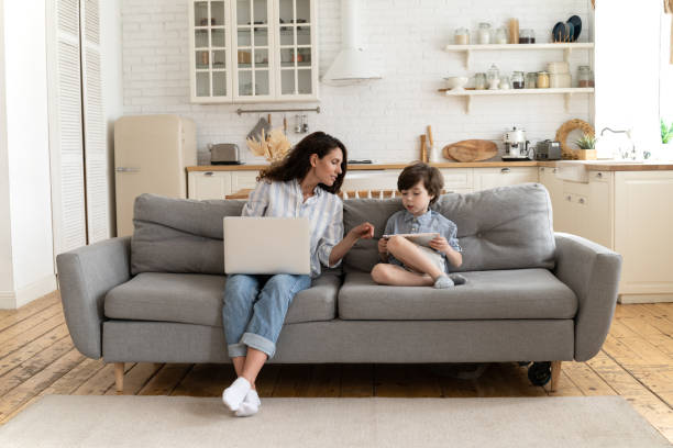 istock Young mom help son with online learning from home. Freelancer mother looking at son play on tablet 1323567084