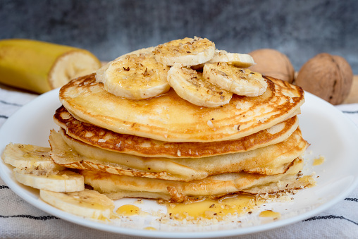 Banana pancake, drenched in honey or maple syrup, with banana slices on top