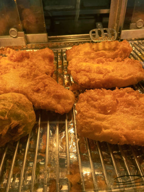 istock Close-up image of battered cod, haddock, sausages and fishcakes, fish and chip shop warming cabinet display with sliding door, elevated view, focus on foreground 1323568209
