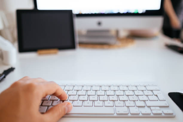 istock Man working on desktop pc with blank screen on table in office interior building 1323569565