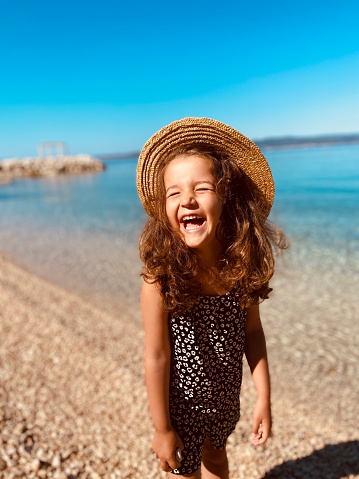 Little girl posing by the sea with a hat