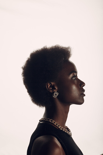 Close up profile portrait of african american woman with afro hairstyle on white studio background.