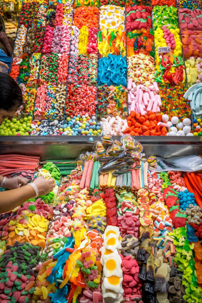 Candy stand with colorful candies sprawled out on display while worker puts on gloves in Barcelona Catalonia Spain October 2015.
