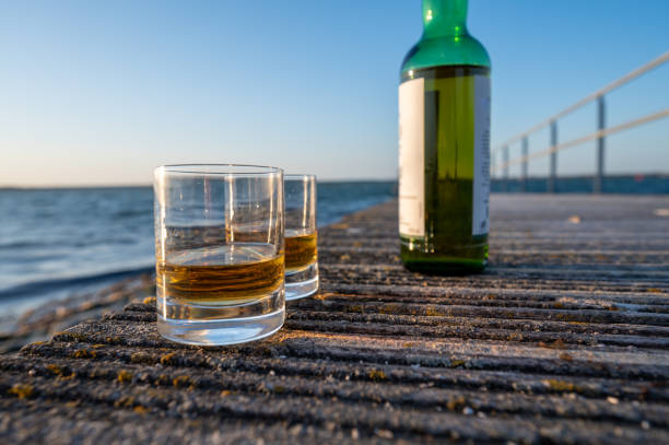 trinken von single malt scotch whisky bei sonnenuntergang mit blick auf smeer, meer oder fluss, private whisky-touren in schottland, uk - ebb tide stock-fotos und bilder
