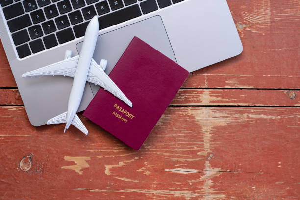 istock Airplane model with passports and laptop computer on wooden table 1323576966