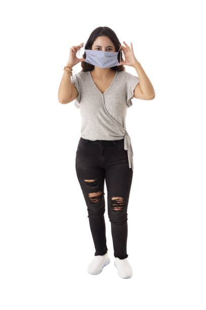 istock Young woman standing and putting on face mask 1323577239
