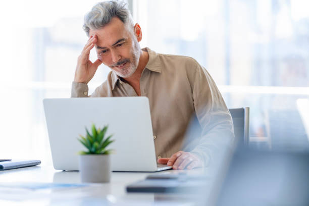 istock Mature businessman working at a desk on a laptop computer. 1323578462